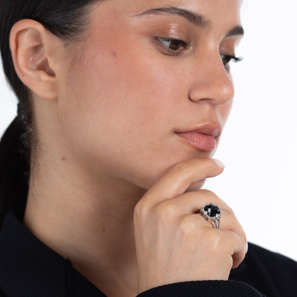 Woman wearing a black onyx ring on her finger with a white background